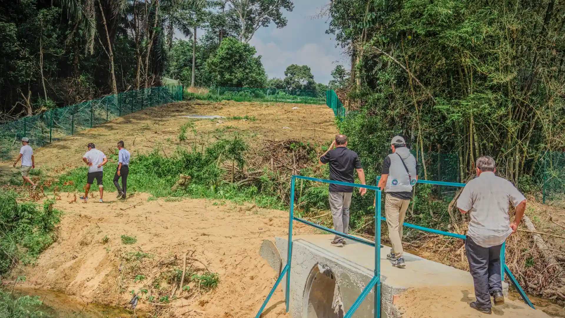 Back side of DAIO Pongamia Johor plantation with two people walking away from the viewer in the foreground.